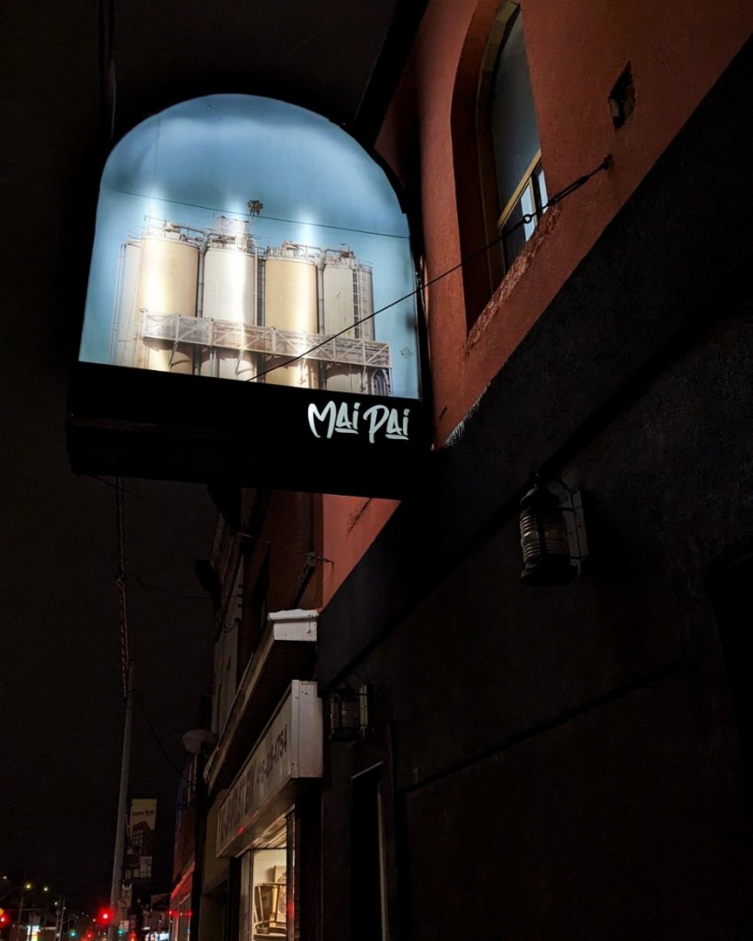 Exterior sign for Maipai in Hamilton at night.