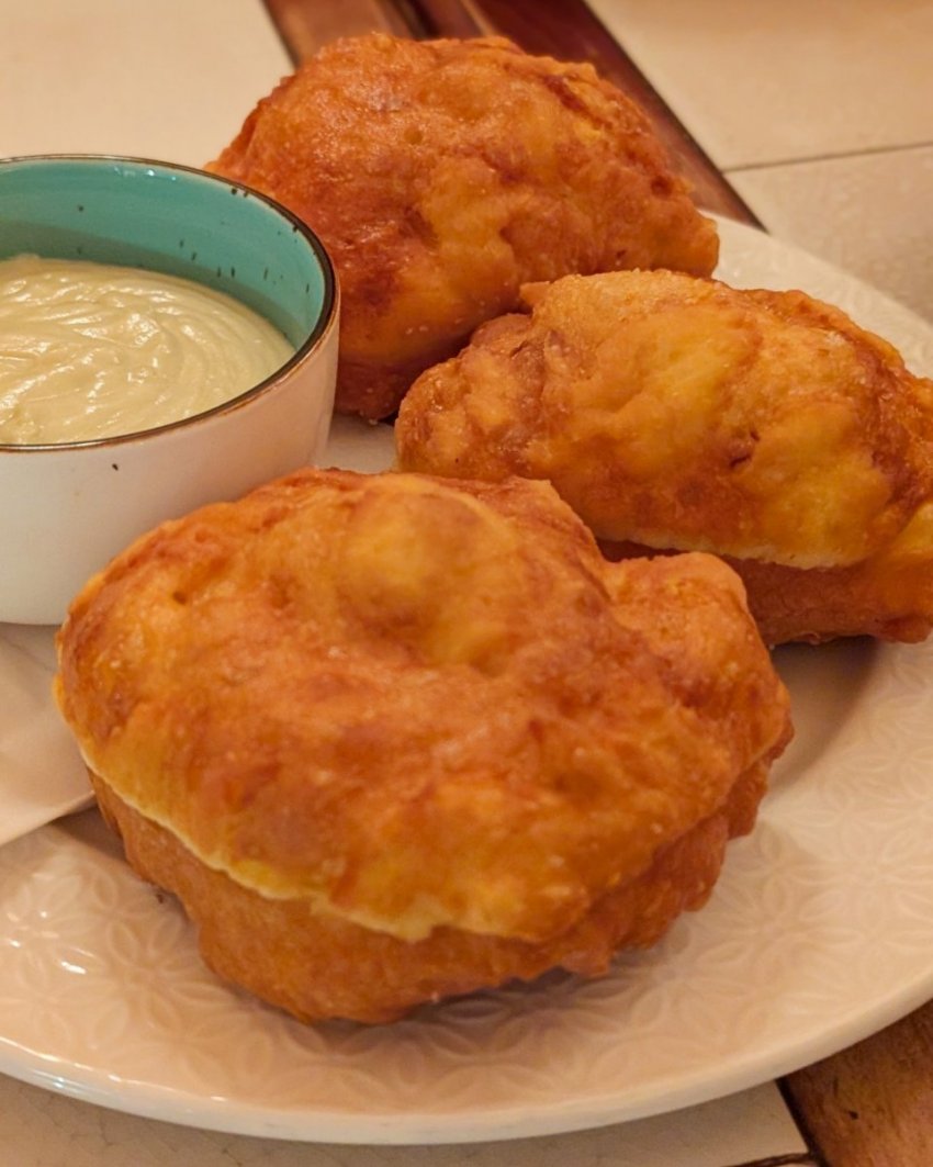 Portrait photo of Mon Ami’s uštipci in Prague, showing the golden fried bread and rich cheese sauce.