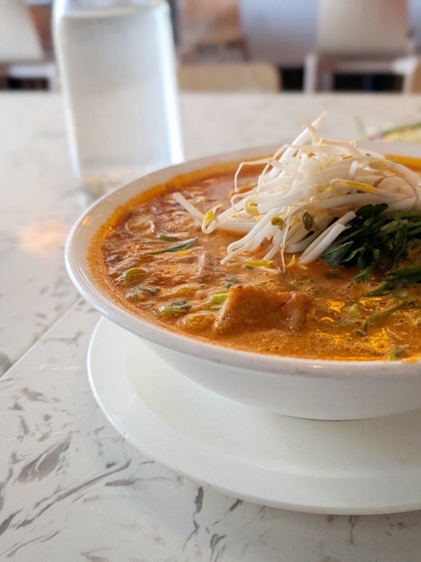 Portrait photo of Nho Saigon’s peanut saté pho, showing the rich broth, noodles and fresh toppings up close.