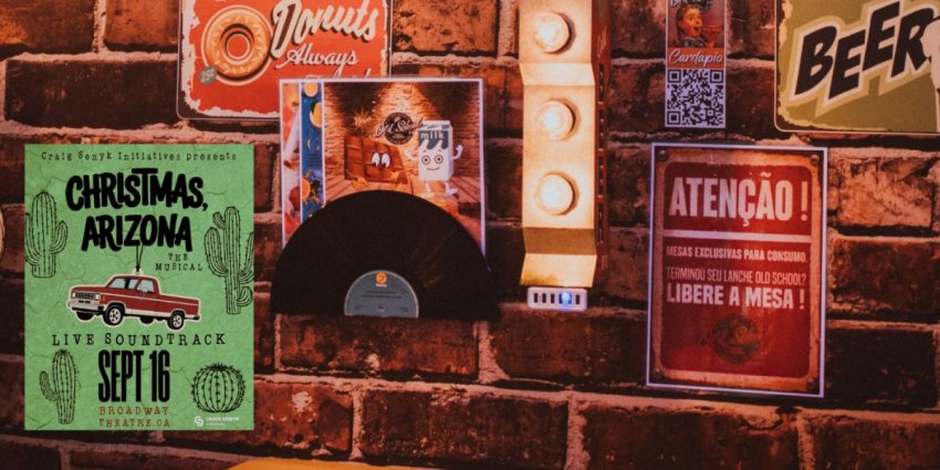Brick bar wall decorated with vintage posters and warm lighting, capturing the aesthetic and inspiration for the dive bar in Christmas, Arizona The Musical.