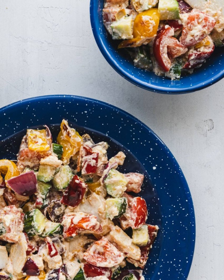 Close up of feta roasted with bell peppers, onion and kohlrabi with cucumbers and tomatoes.