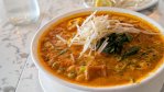 A bowl of peanut saté pho from Nho Saigon in Calgary, filled with rice noodles, broth, herbs and toppings.