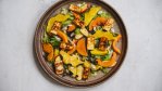 A cermaic brown plate with roast squash, greens, apple slices and grilled halloumi. A recipe from Dan Clapson's cookbook Prairie.
