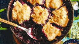 A close-up landscape photo of jammy blueberries topped with soft lemon dumplings.