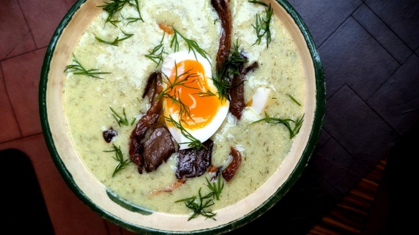 A landscape view of Dan Clapson’s Czech-style Kulajda mushroom soup garnished with fresh dill, crispy oyster mushrooms, and a jammy soft-boiled egg