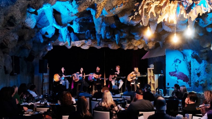 Blue Jay Sessions performers on stage at Blue Grotto Lounge in Hamilton with audience seated during a live songwriter circle.