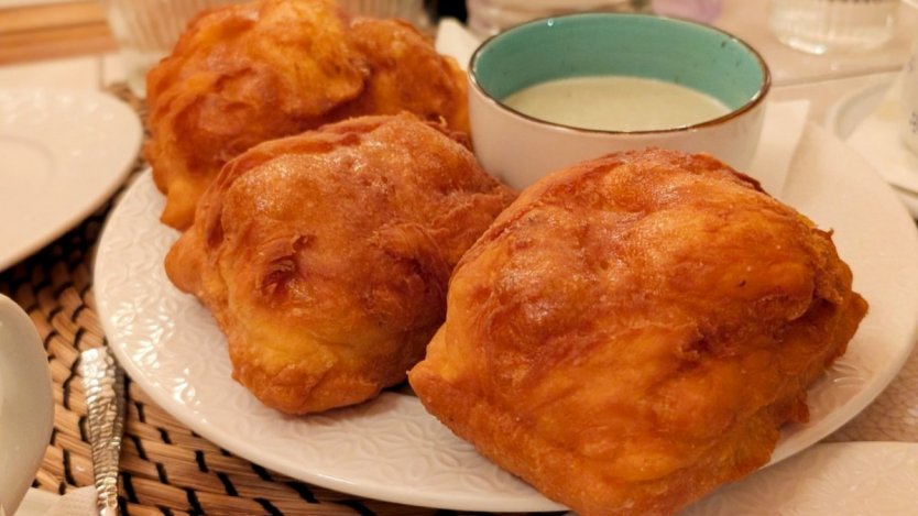 Golden uštipci served at Mon Ami in Prague with a side of creamy cheese sauce for dipping.