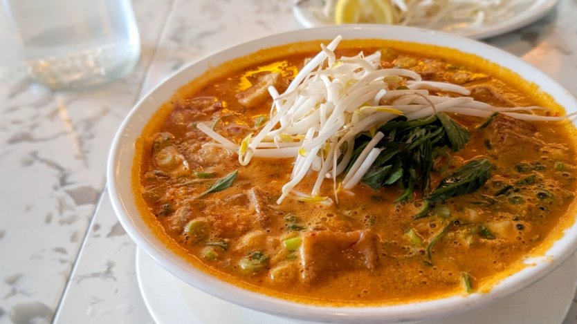 A bowl of peanut saté pho from Nho Saigon in Calgary, filled with rice noodles, broth, herbs and toppings.