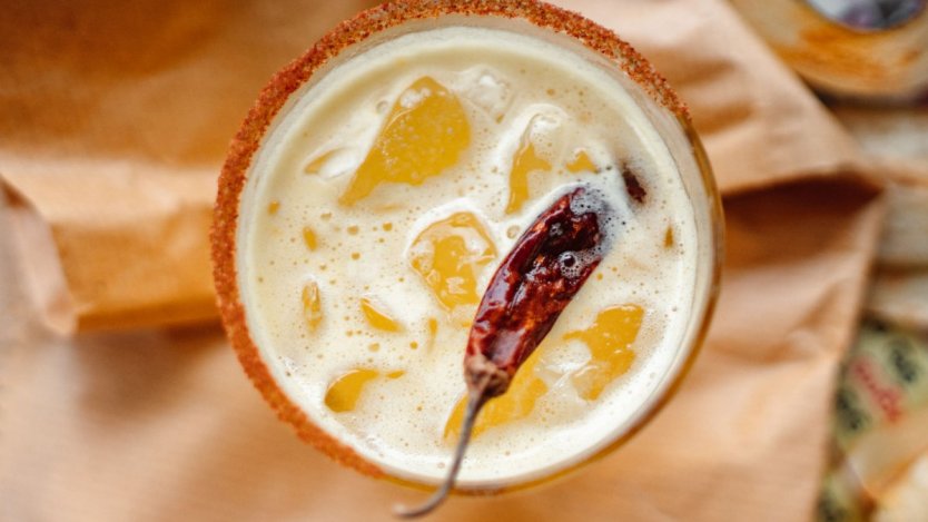 Overhead top-down view of a Plain Jane Gold cocktail in a chilled coupe glass with a dehydrated citrus wheel garnish on a rustic surface.