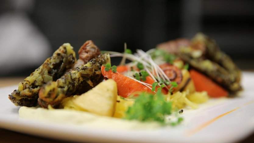 Wood fired root vegetables with winter squash, wild rice latke, pork belly and micro arugula. Photo by Kevin Kossowan.