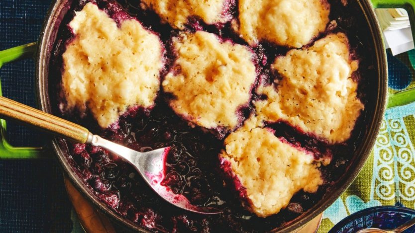 A close-up landscape photo of jammy blueberries topped with soft lemon dumplings.