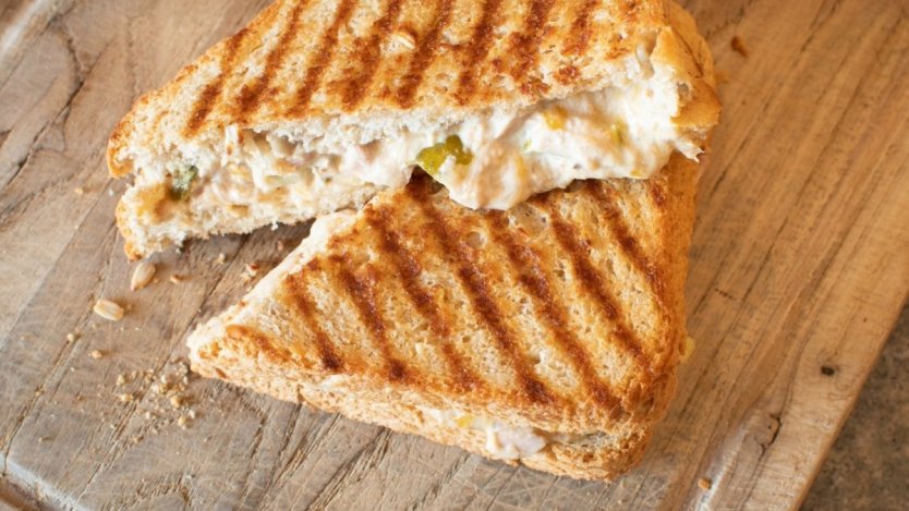 Grilled tuna melt sandwich with creamy filling and pickles on toasted bread