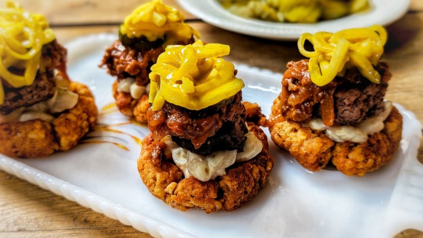 Spicy Garbage Plate-inspired tater tot cups topped with burger, meat sauce, macaroni salad, mustard-macerated onions and pickles